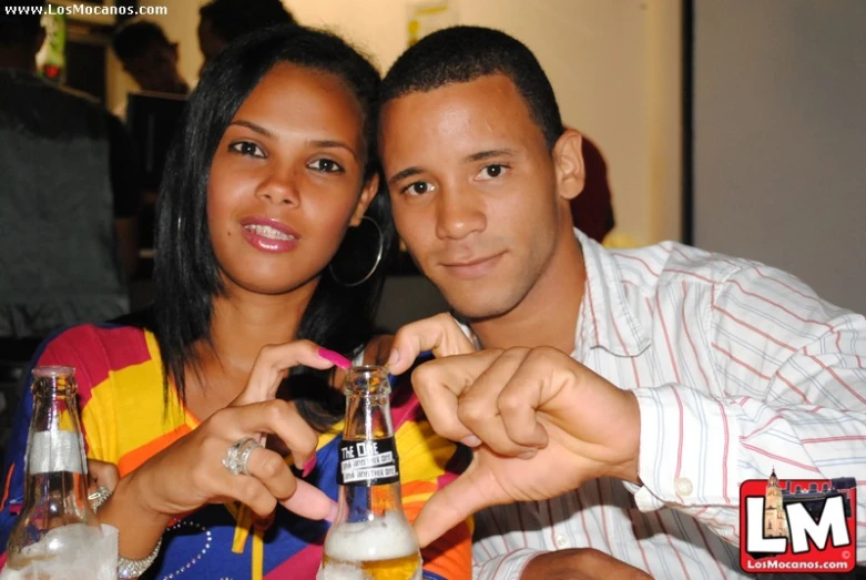 a woman standing next to a man holding a bottle of alcohol