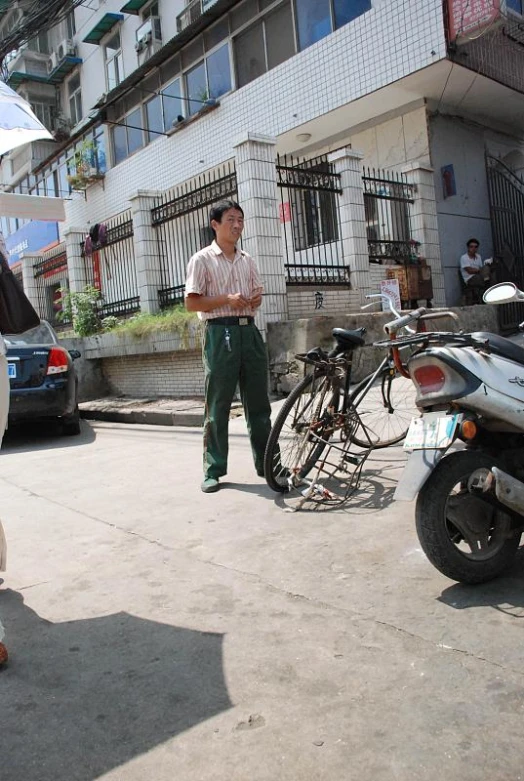 a man wearing white pants and brown sandals walking on the sidewalk