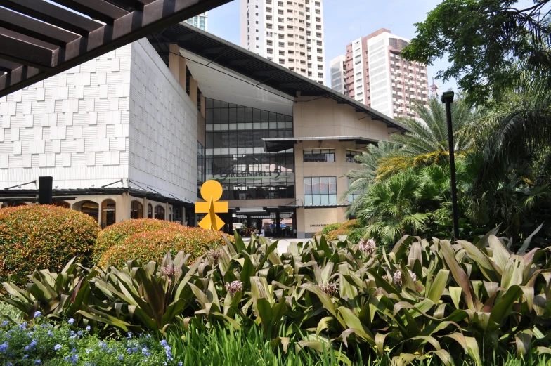 plants surrounding a building near a large statue