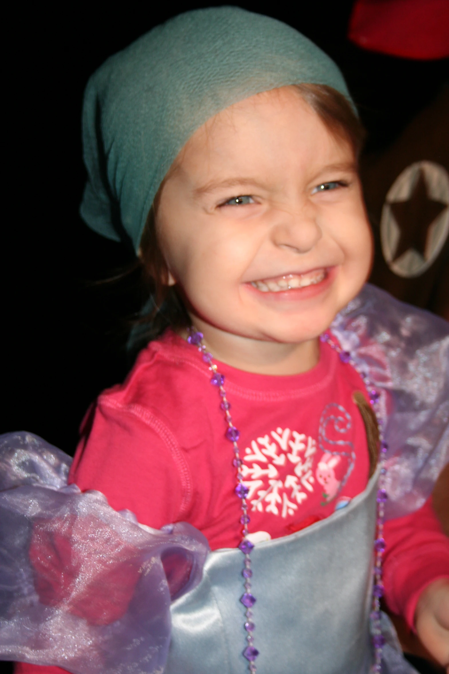 a  in a pink shirt smiles as she holds a small silver cup