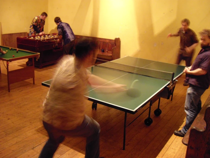 a group of people play ping pong in a room