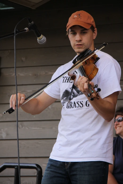 a man wearing an orange hat while playing the violin