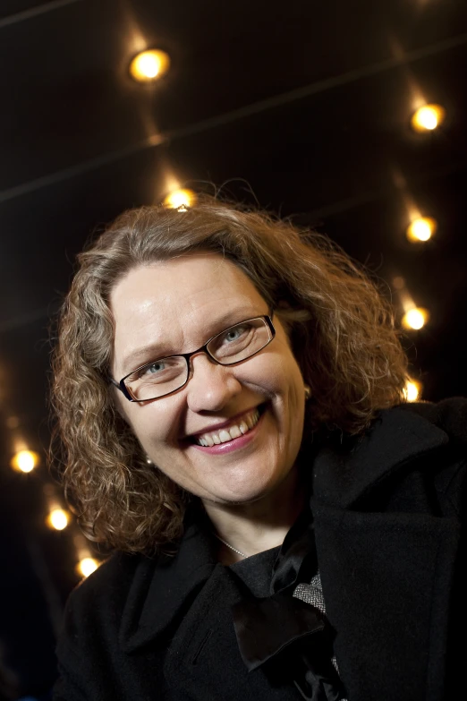 a woman in glasses with long hair smiles into the camera