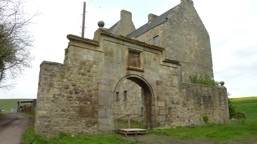 an old stone building with a gate next to a field