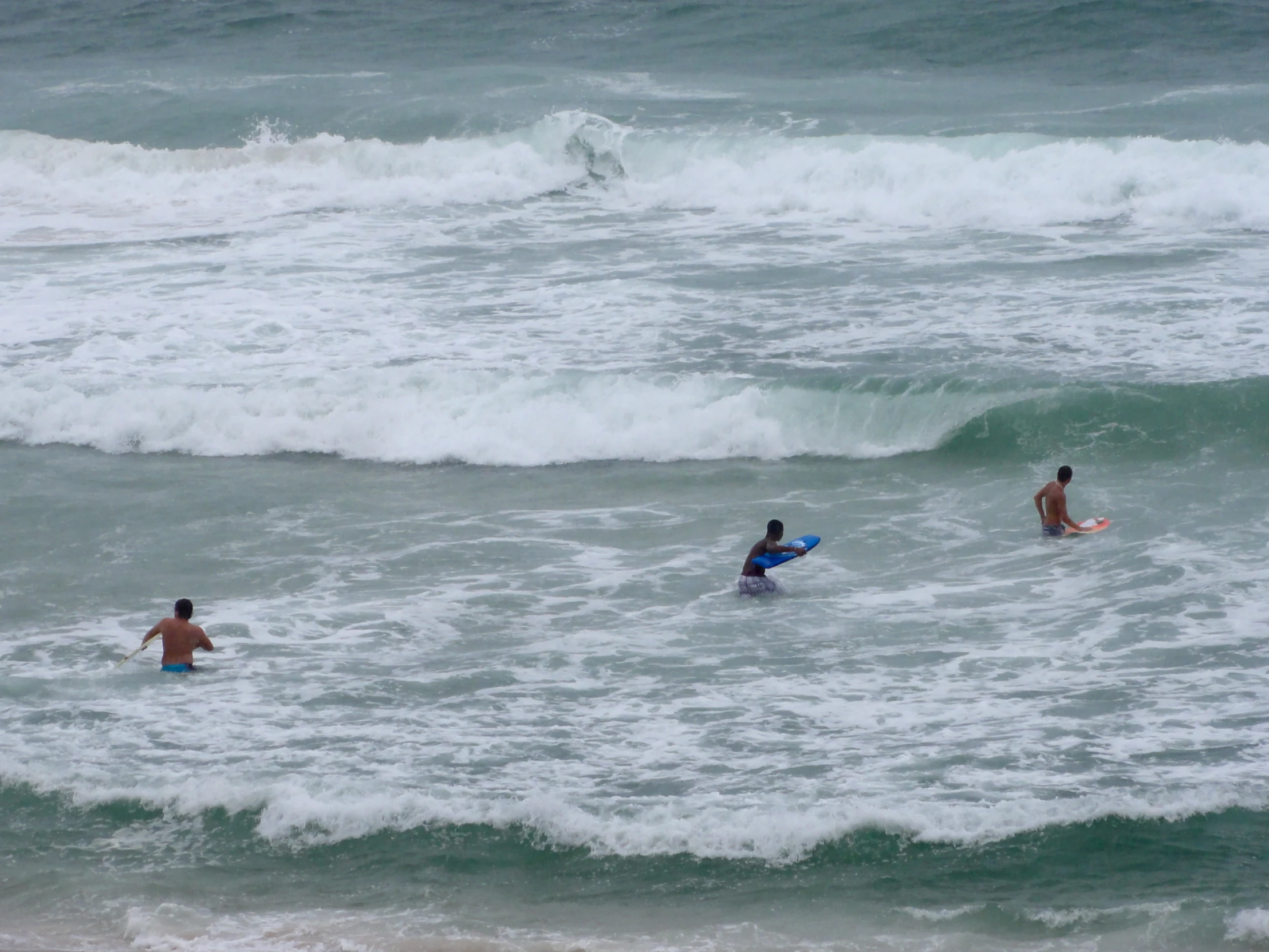 three people that are in the ocean with surfboards