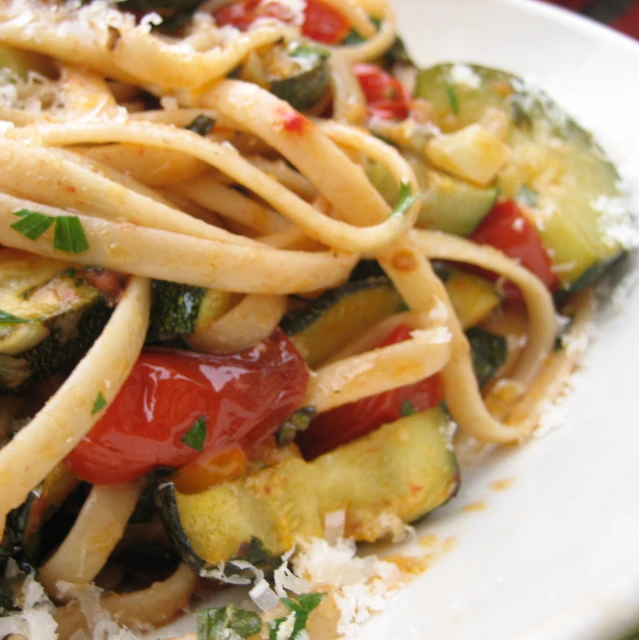 an pasta dish covered with vegetables, onions, and sauce