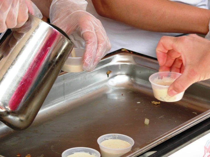 a person in white gloves is pouring some food