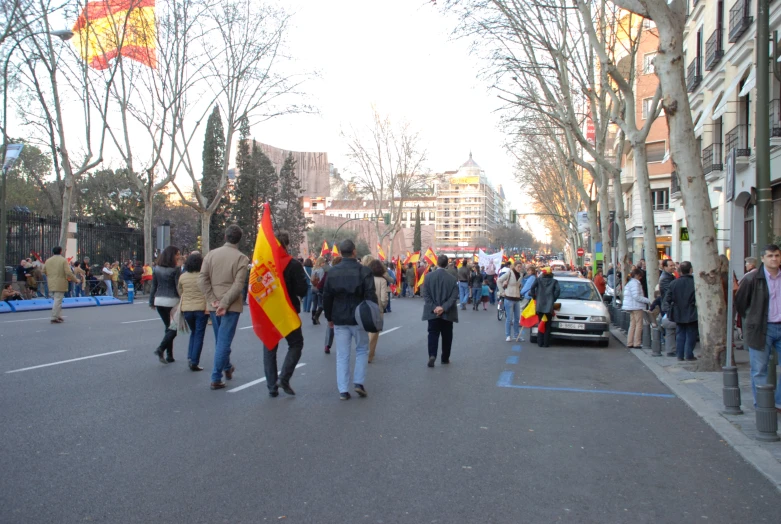 people walking down the street holding flags and other objects