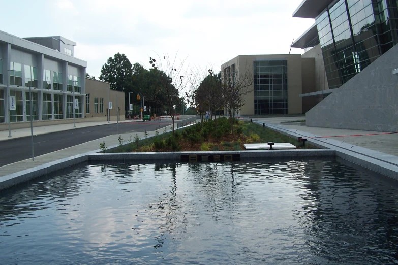 a small pond sits empty between two large buildings
