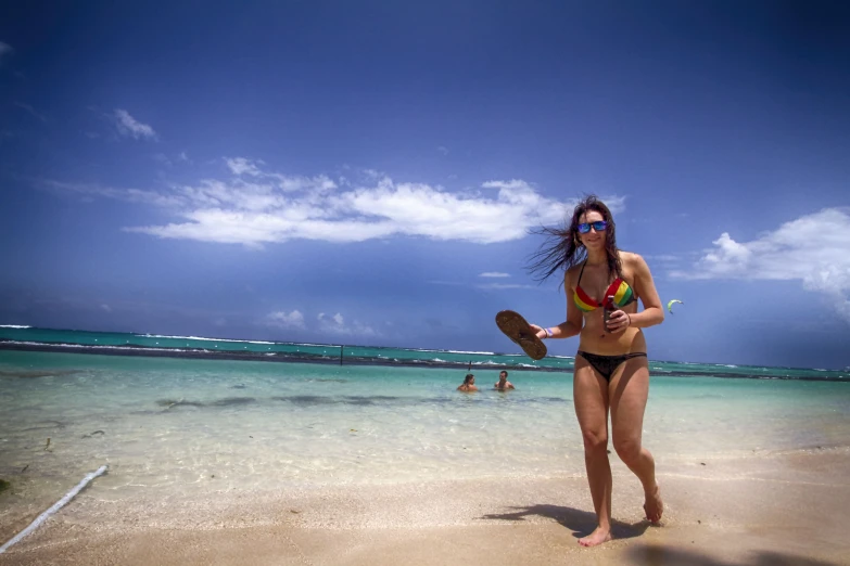 a woman in a bikini holding a paddle on a beach