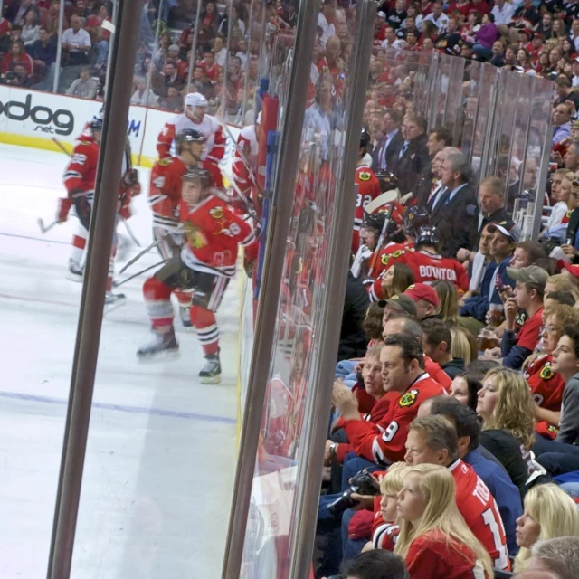 hockey players are standing behind the barrier in front of a crowd