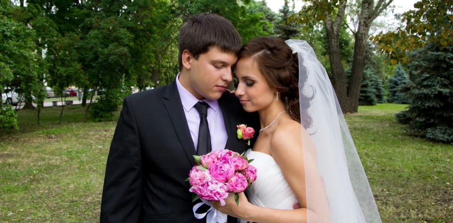 bride and groom pose with their hands over the bride's shoulder