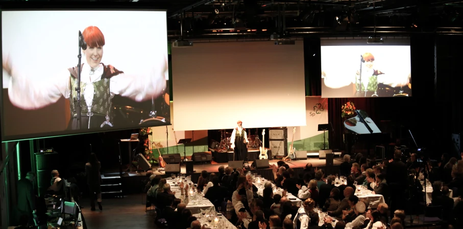 large crowd watching two people present their own picture on large video screens