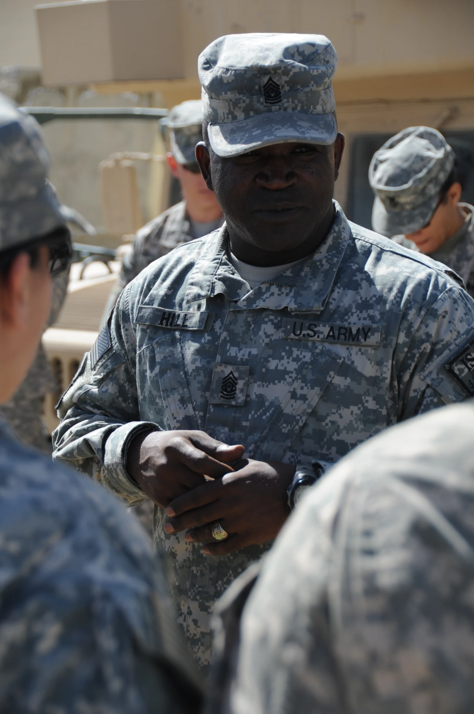a man in military fatigues standing around a bunch of other men