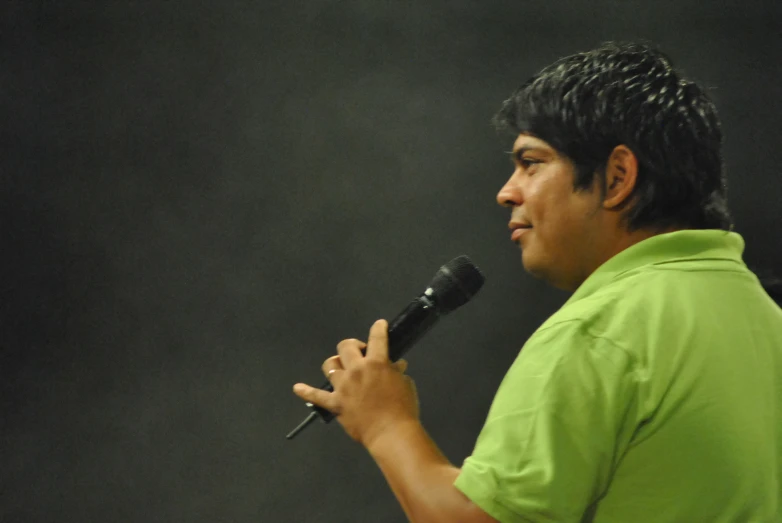 a man in green shirt holding a microphone