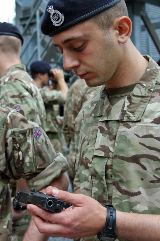 a man in a military uniform looking down at his cell phone