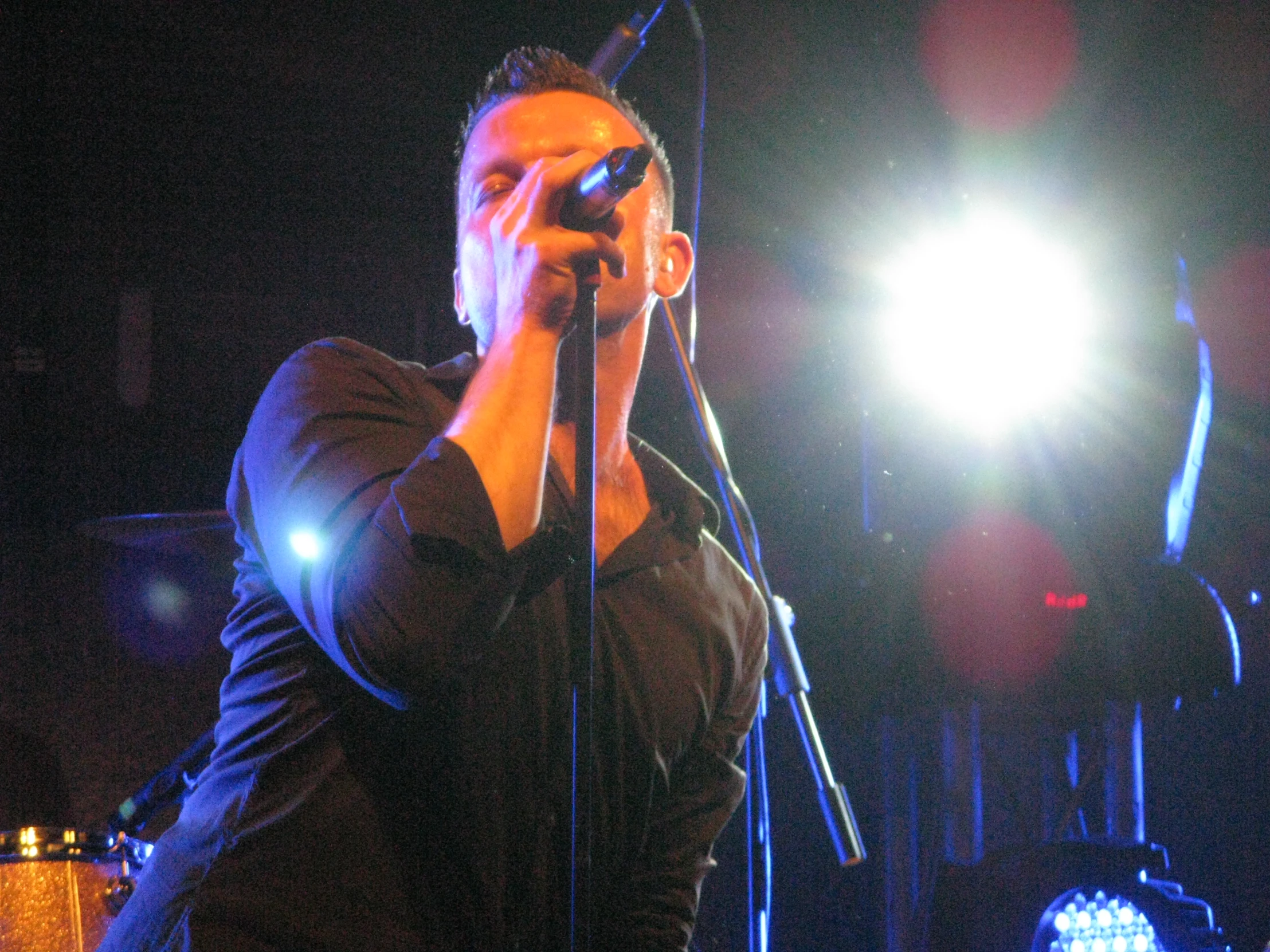 a man standing on stage singing into a microphone