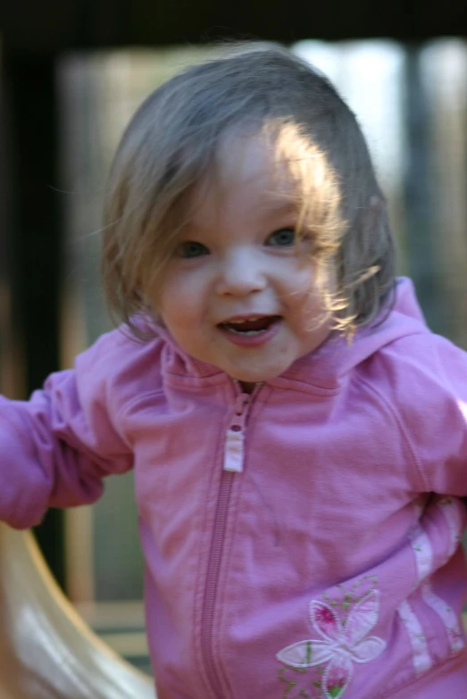 a toddler girl walking around in her pink jacket