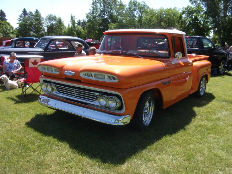 an orange classic pickup truck parked in a field