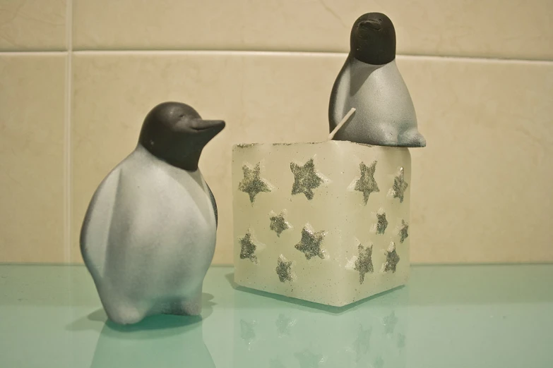 a small ceramic penguin figurine next to an ice block