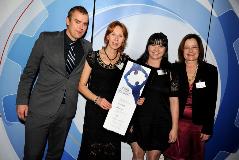 four people posing with their certificate at a convention