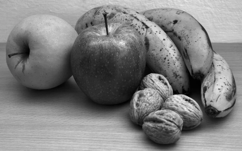 the black and white pograph depicts nuts, fruit, and apple