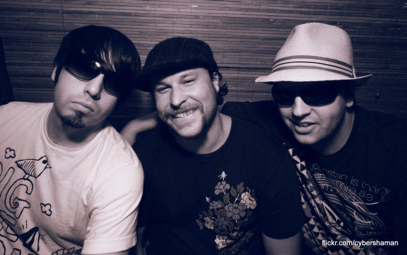 three young men sitting together smiling and taking a po