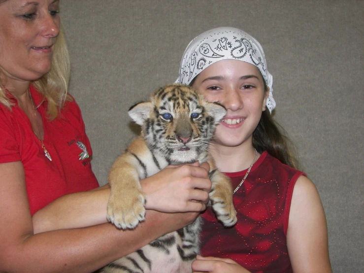 a woman holding a baby tiger cub in her hands