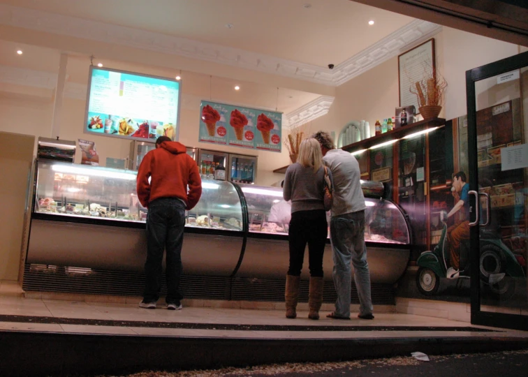 three people standing in a line next to the food counter