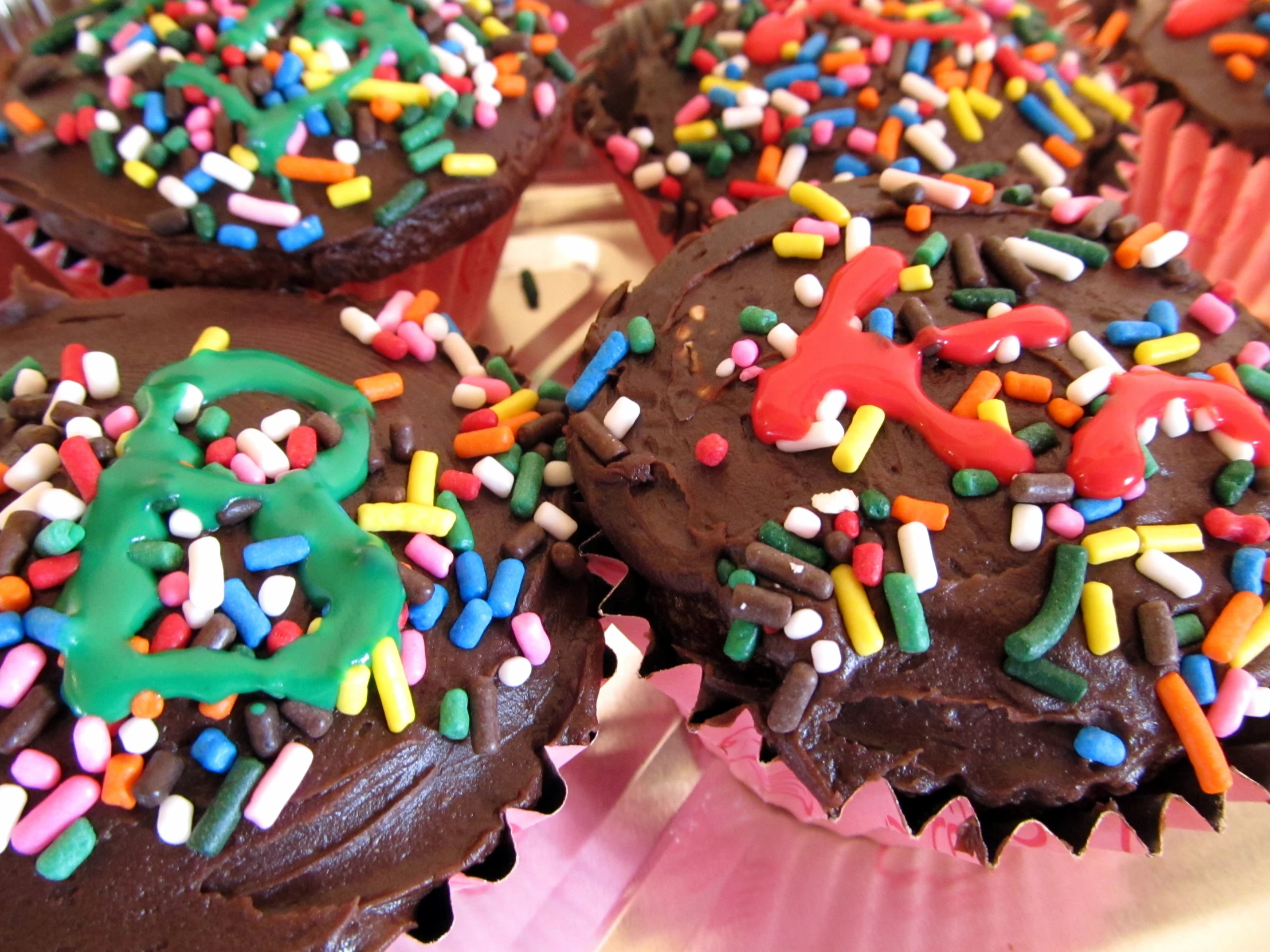 many chocolate cupcakes have sprinkles on them