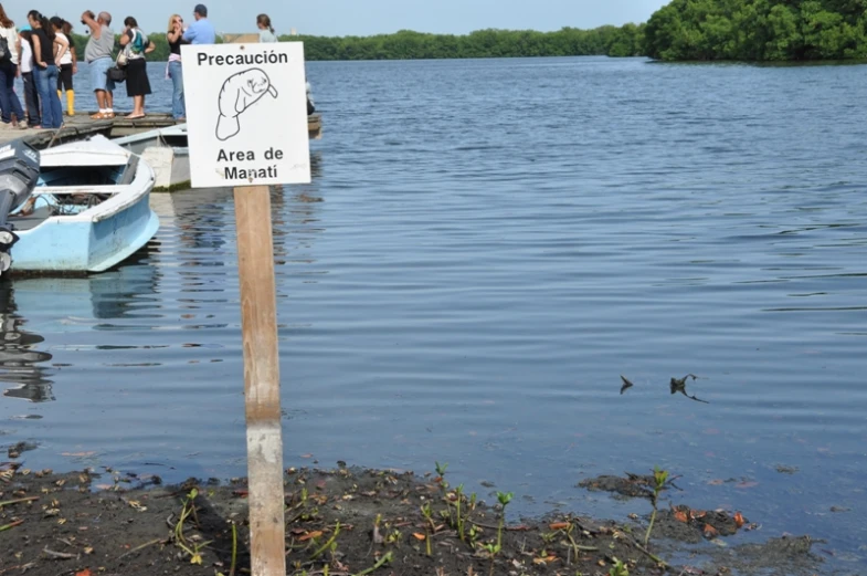 a sign sitting in front of water next to a boat