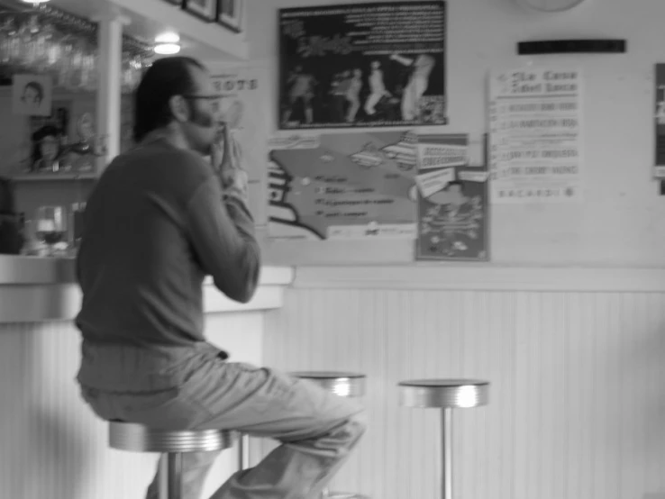 a man sitting on a stool talking on a cell phone