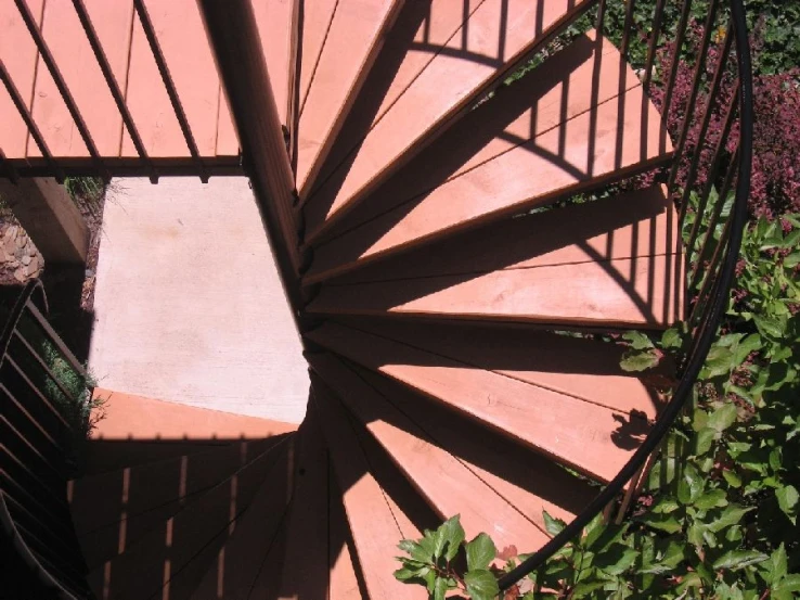 the circular railing of a deck at the bottom of a pink building