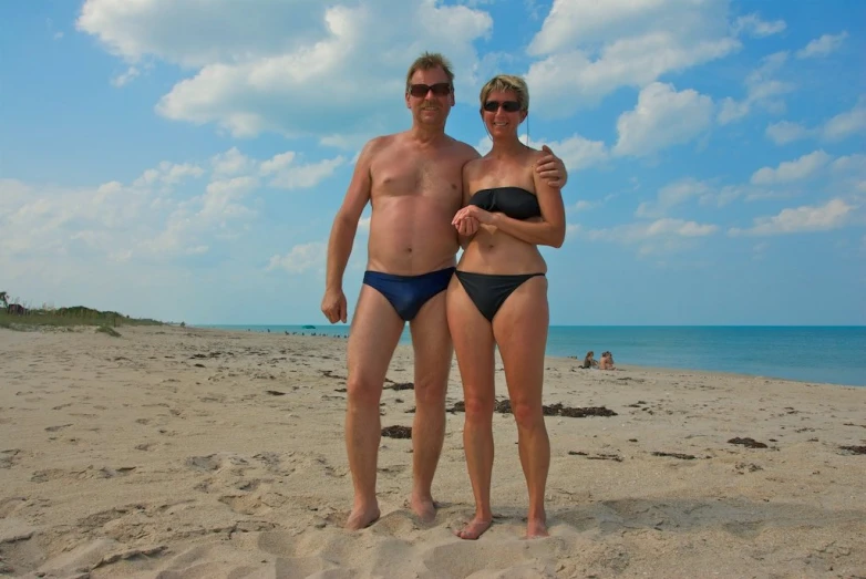 two people standing on a beach posing for the camera