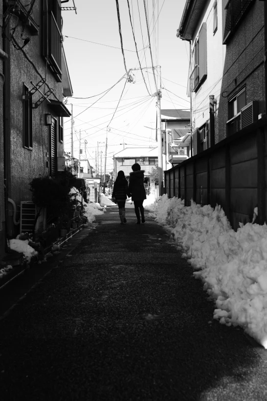 two people walking down a city street under wires