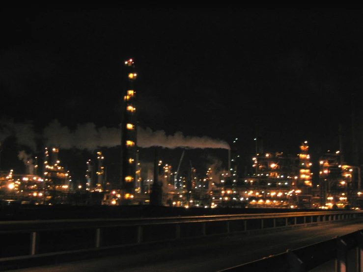 industrial plant lit up at night over a city