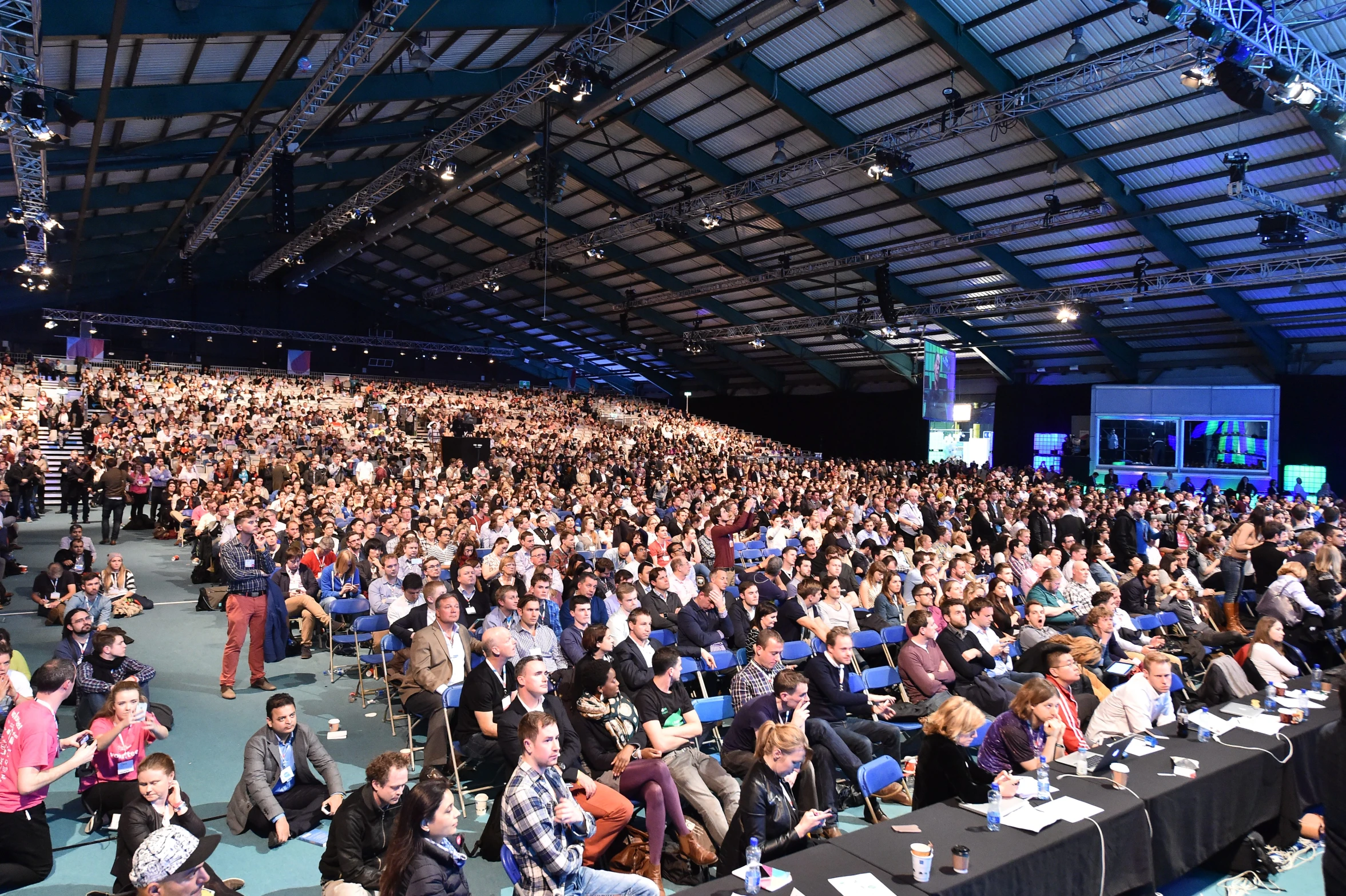 people sitting in rows at tables in an indoor event