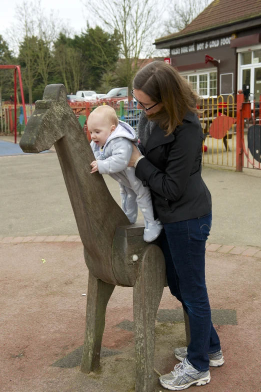 a woman holding a small child on top of a statue of a deer