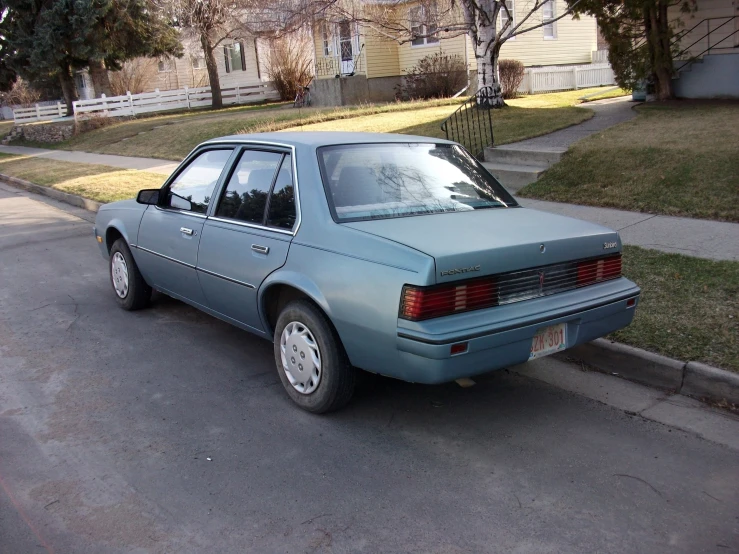 a pale blue ford pinto coupe is parked at a corner