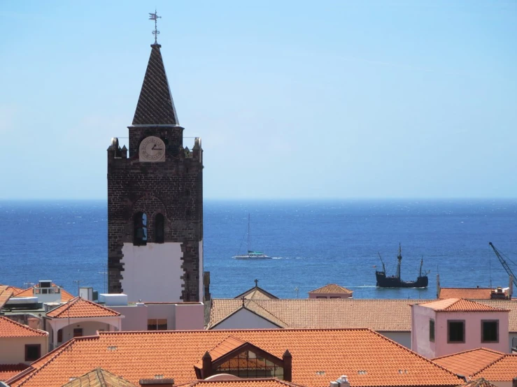 a church steeple sitting high above a city next to the ocean