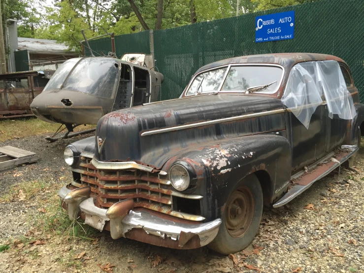 an old, rusted car sitting in a junk yard next to another one