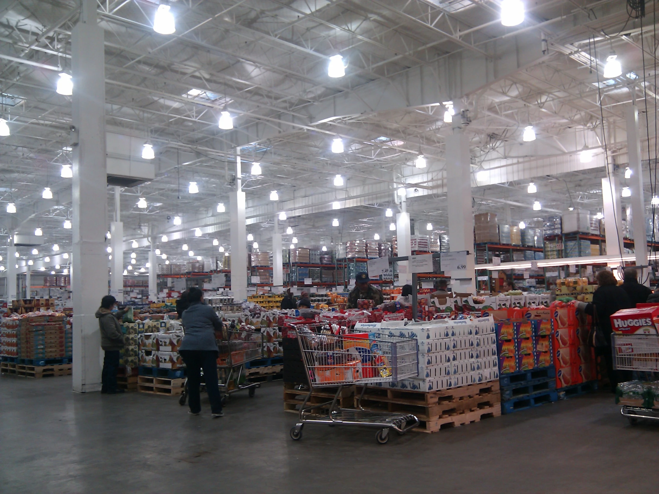 many light bulbs are in the ceiling and some people are shopping