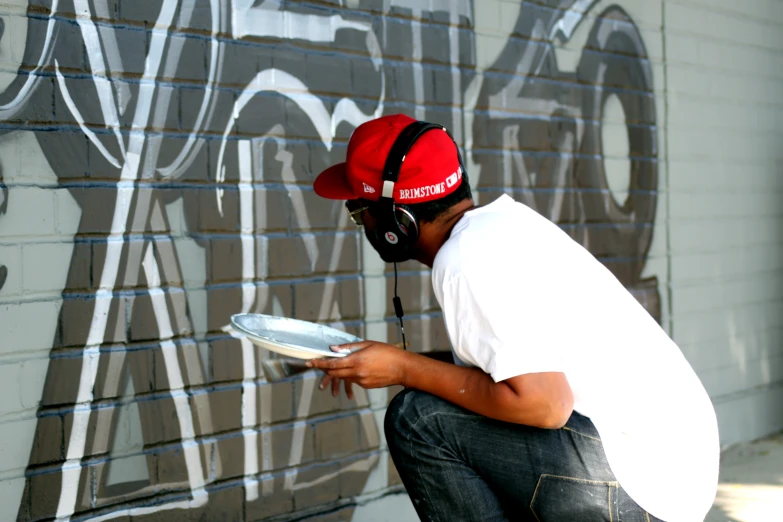 a man is playing with soing in front of a graffiti - art wall