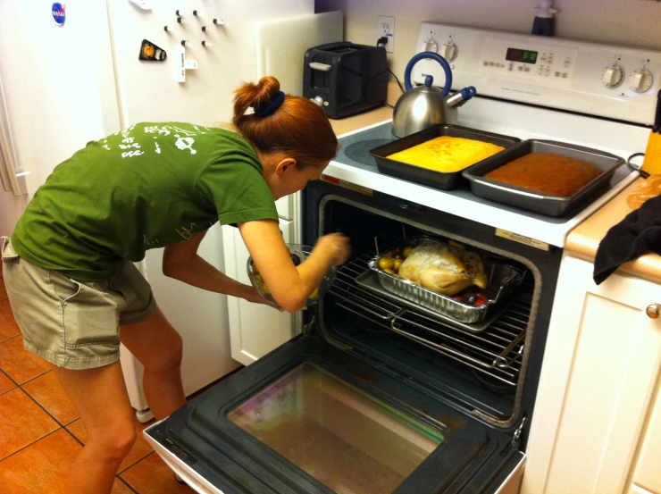 a young lady placing an item into the oven
