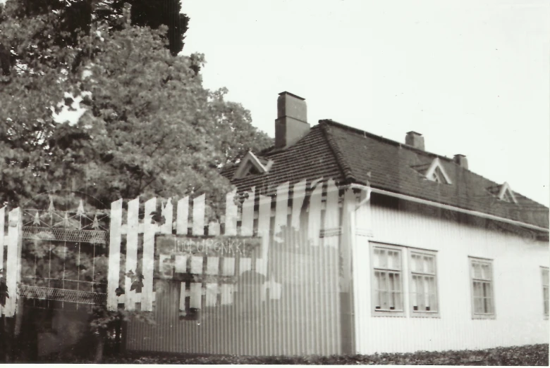 an old picture of a house with fence in front