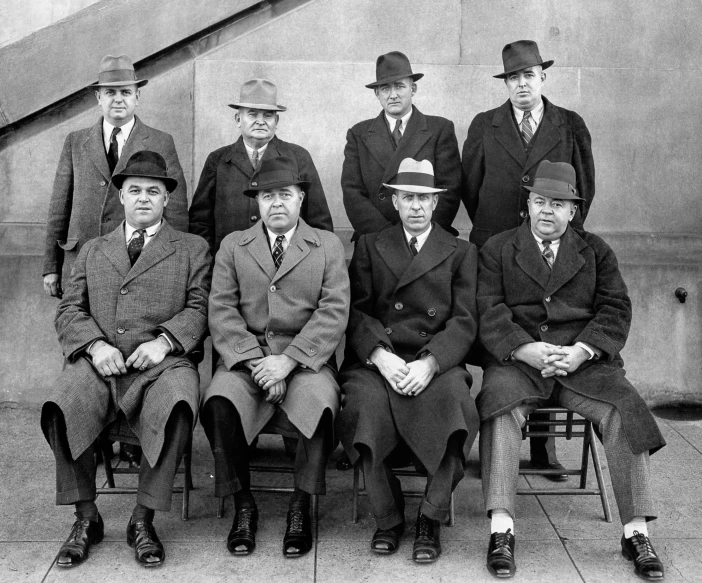 a group of men in suits sitting on top of chairs