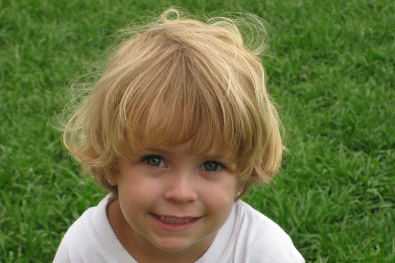 a young blonde child with a mohawk standing in the grass