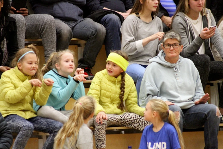 a group of girls sitting next to each other in a crowd