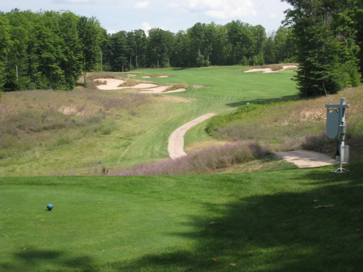 a green golf field has a walkway going down the hill