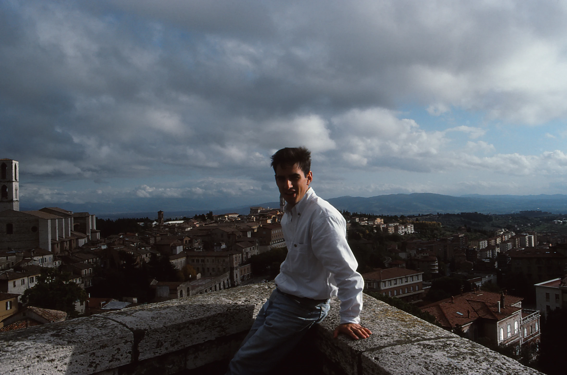 a man sitting on top of a roof with a cellphone to his ear